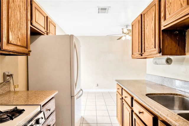 kitchen with a ceiling fan, white appliances, light tile patterned floors, a sink, and baseboards