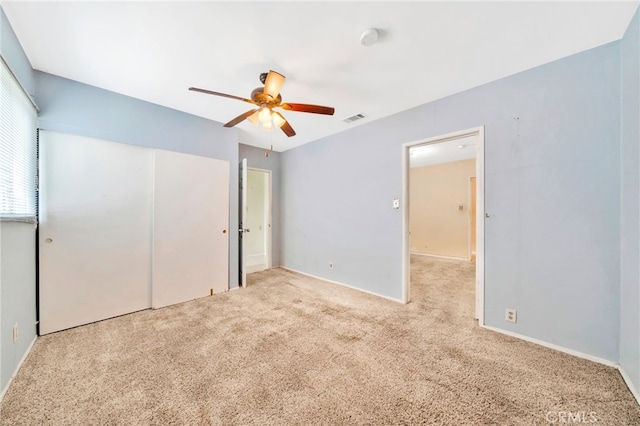 unfurnished bedroom with carpet flooring, a closet, baseboards, and a ceiling fan