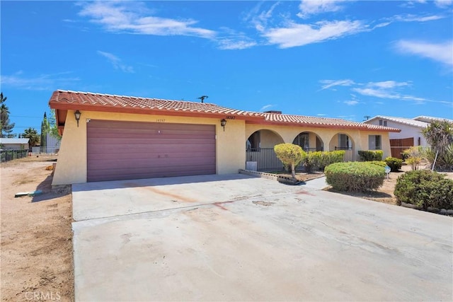 mediterranean / spanish-style house with an attached garage, driveway, stucco siding, and a tiled roof