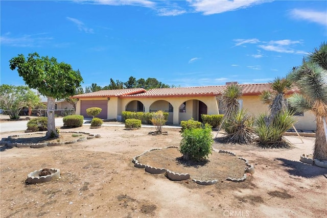 mediterranean / spanish-style home with stucco siding, a garage, and a tile roof