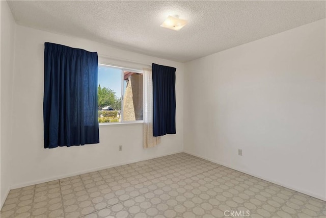 unfurnished room with a textured ceiling and tile patterned floors