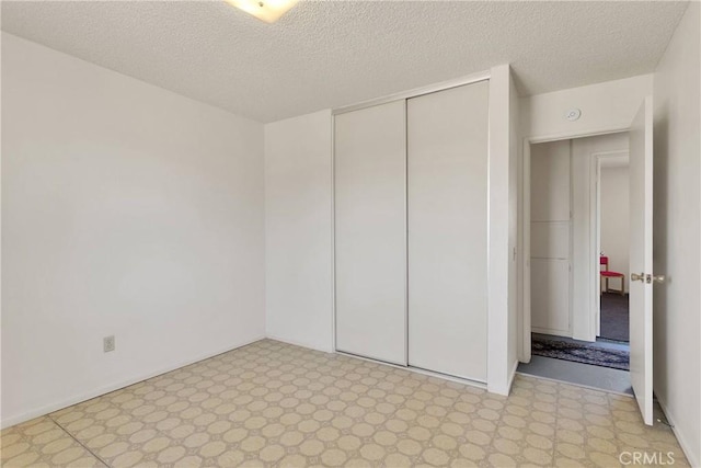 unfurnished bedroom with a textured ceiling, a closet, and light floors