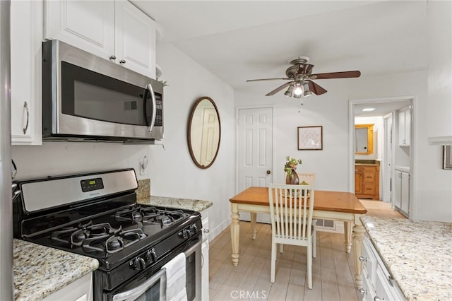 kitchen with stainless steel appliances, ceiling fan, white cabinets, baseboards, and light stone countertops