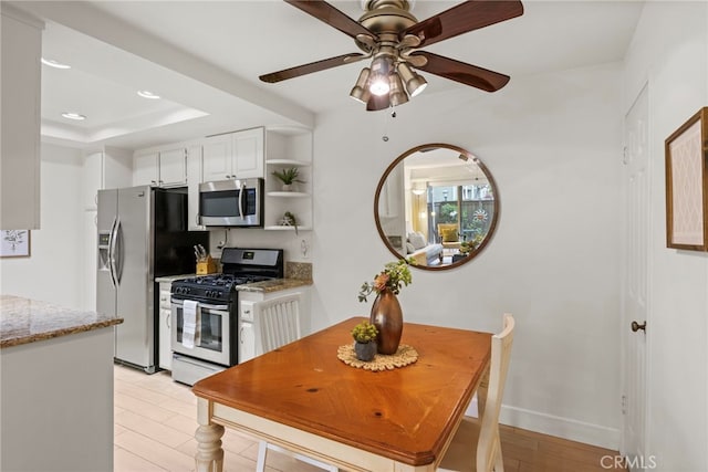 kitchen featuring appliances with stainless steel finishes, white cabinets, a ceiling fan, light stone counters, and open shelves