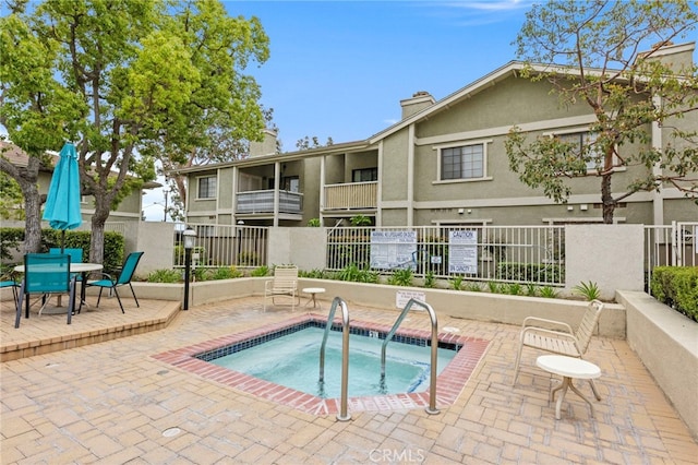 view of swimming pool with a community hot tub, fence, and a patio area