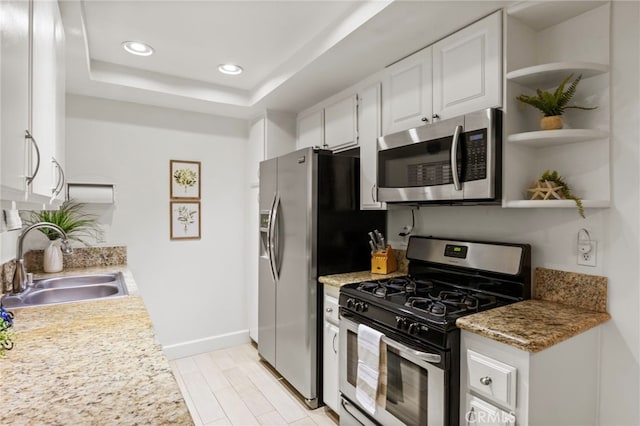 kitchen featuring stainless steel appliances, a sink, recessed lighting, open shelves, and white cabinets