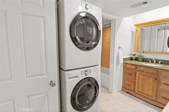 clothes washing area with estacked washer and dryer and light tile patterned floors