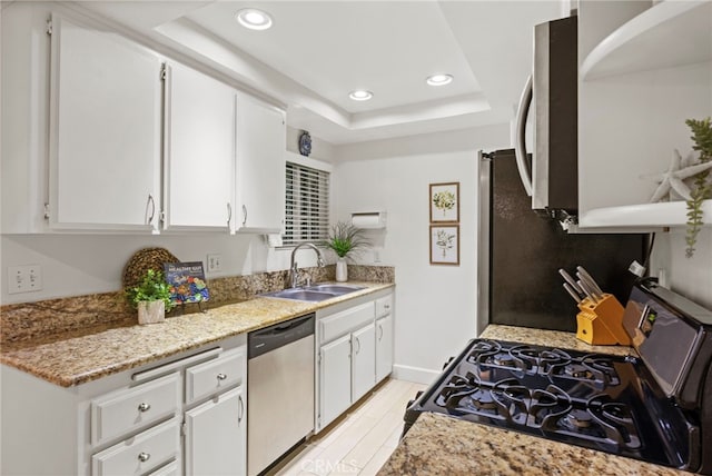 kitchen with appliances with stainless steel finishes, a sink, white cabinetry, recessed lighting, and a raised ceiling