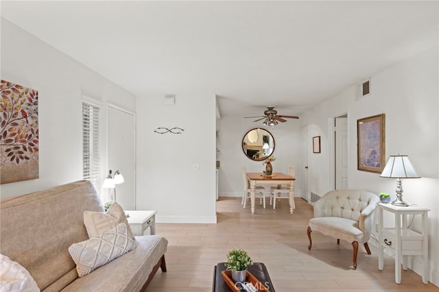 living room with light wood-style flooring, ceiling fan, and baseboards