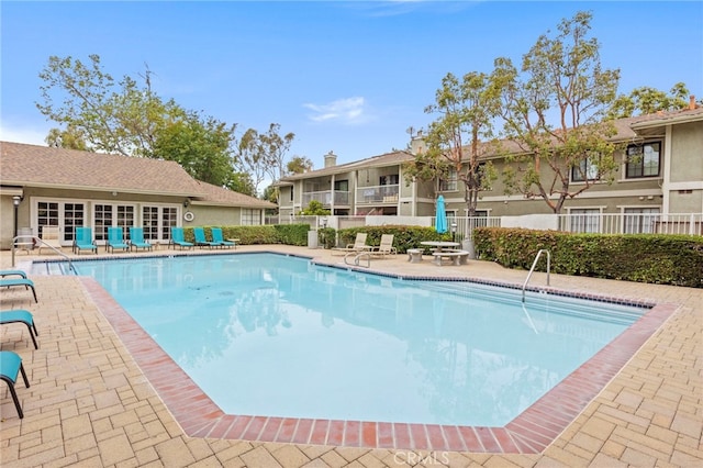 community pool with fence and a patio