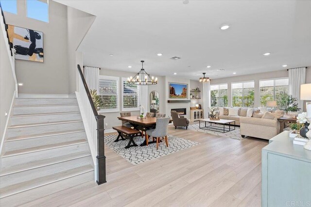 940 Lindbergh Dr, San Marcos, CA 92069 - dining space with a chandelier, light wood-style floors, recessed lighting, stairway, and a warm lit fireplace