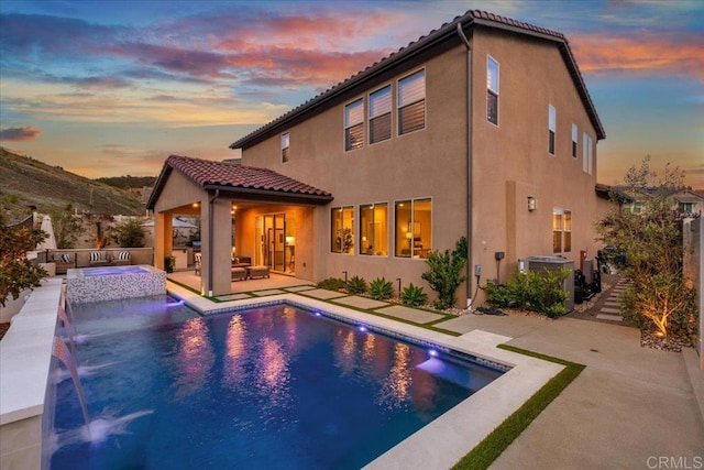 940 Lindbergh Dr, San Marcos, CA 92069 - back of property at dusk with a patio, stucco siding, a tile roof, and a pool with connected hot tub