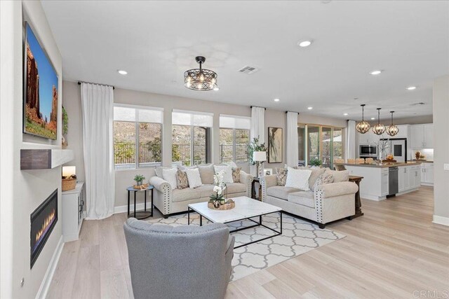 940 Lindbergh Dr, San Marcos, CA 92069 - living room with healthy amount of natural light, light wood-type flooring, recessed lighting, a glass covered fireplace, and a chandelier