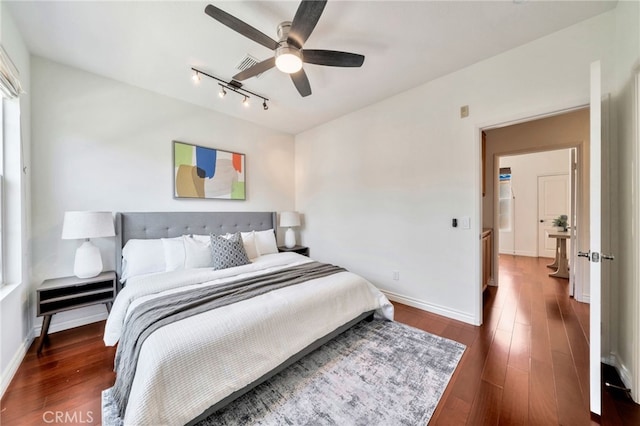 bedroom featuring track lighting, wood finished floors, and baseboards