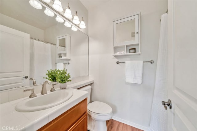 bathroom featuring toilet, wood finished floors, and vanity