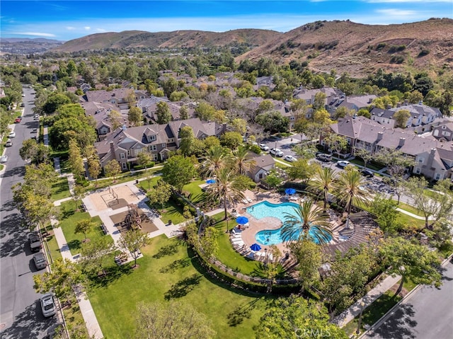 aerial overview of property's location with a pool, a mountain backdrop, and nearby suburban area