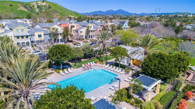 aerial view of property and surrounding area featuring a mountain backdrop, nearby suburban area, and a pool