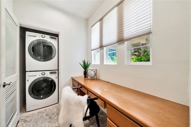 laundry room with stacked washer / dryer and a desk