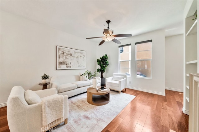 living area with a ceiling fan, baseboards, and wood finished floors