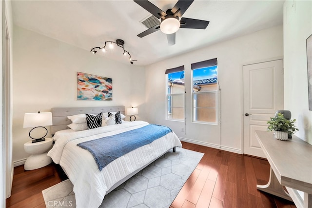bedroom featuring wood-type flooring, track lighting, and baseboards