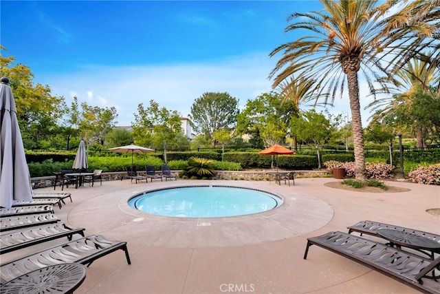 community pool with a patio area and fence