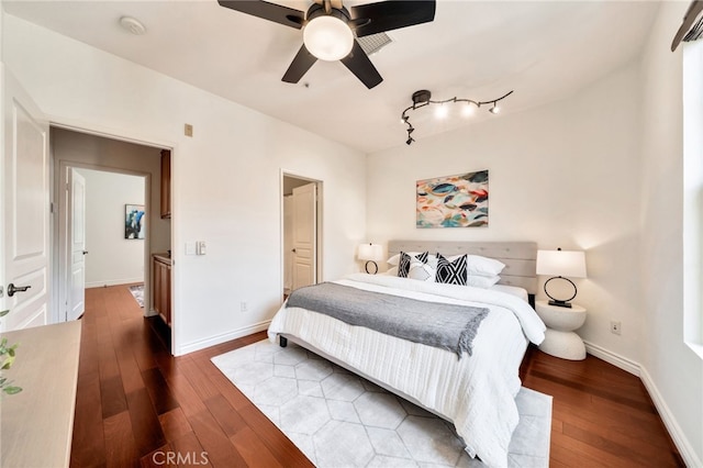 bedroom featuring hardwood / wood-style flooring, baseboards, rail lighting, and a ceiling fan