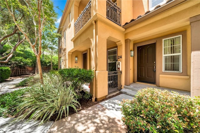 property entrance featuring a balcony and stucco siding