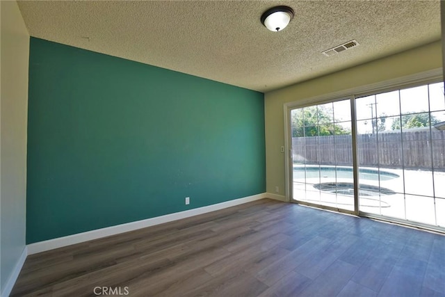 unfurnished room with wood finished floors, a textured ceiling, and baseboards