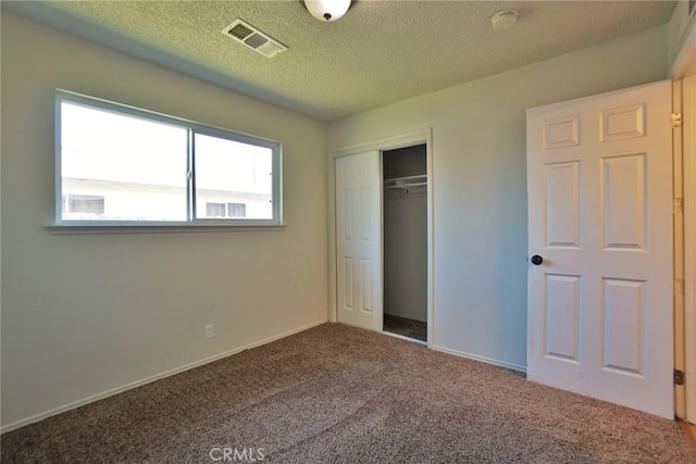 unfurnished bedroom with carpet, a closet, a textured ceiling, and baseboards