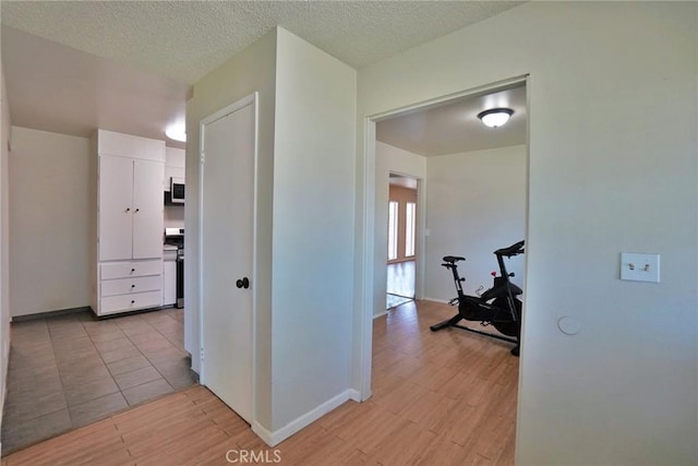 hall featuring baseboards and light tile patterned floors