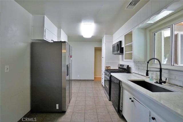 kitchen featuring stainless steel appliances, a sink, white cabinets, and decorative backsplash