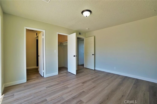 unfurnished bedroom featuring wood finished floors, a textured ceiling, baseboards, and a closet
