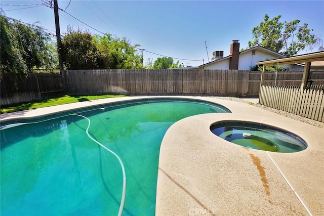 view of swimming pool with an in-ground hot tub and a fenced backyard