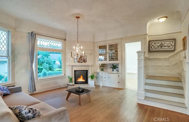 1151 W 14th St, San Pedro, CA 90731 - living room featuring a chandelier, light wood-type flooring, a textured ceiling, stairway, and healthy amount of natural light