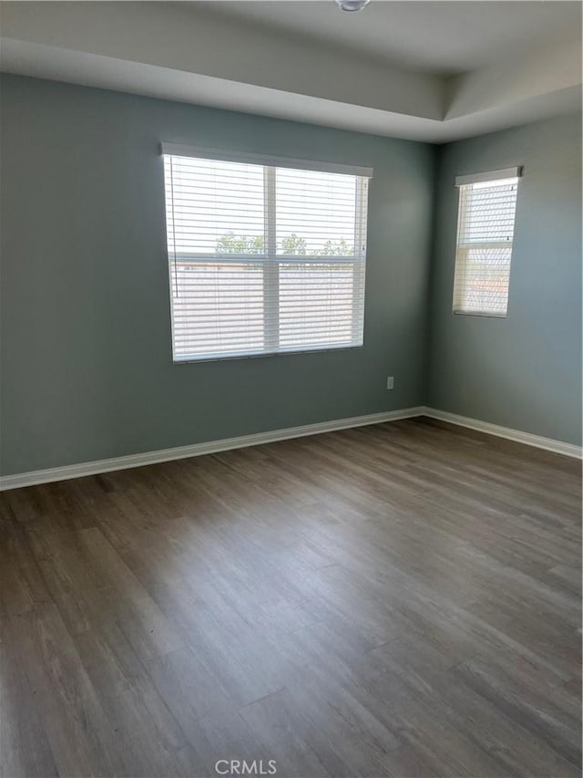 unfurnished room featuring dark wood-type flooring and baseboards