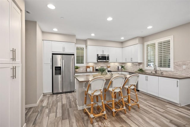 16 Abarrota St, Rancho Mission Viejo, CA 92694 - kitchen featuring appliances with stainless steel finishes, a sink, light wood finished floors, a breakfast bar area, and tasteful backsplash