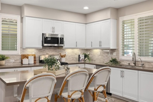 16 Abarrota St, Rancho Mission Viejo, CA 92694 - kitchen with stainless steel microwave, a sink, stove, dark countertops, and white cabinets