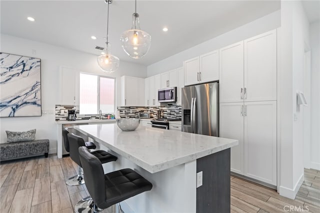 54060 Avenida Madero Ln, Quinta, CA 92253 - kitchen with stainless steel appliances, backsplash, white cabinetry, a center island, and recessed lighting