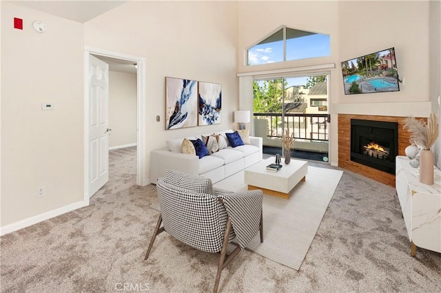 5530 Owensmoutth Ave Unit 306, Woodland Hills, CA 91367 - carpeted living room featuring a towering ceiling, a warm lit fireplace, and baseboards