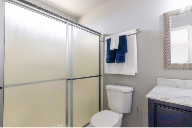 full bath featuring toilet, a stall shower, and vanity