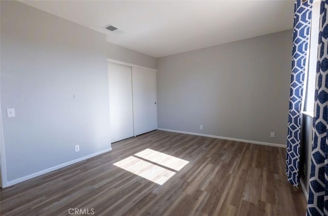 unfurnished bedroom with wood finished floors, baseboards, and a closet