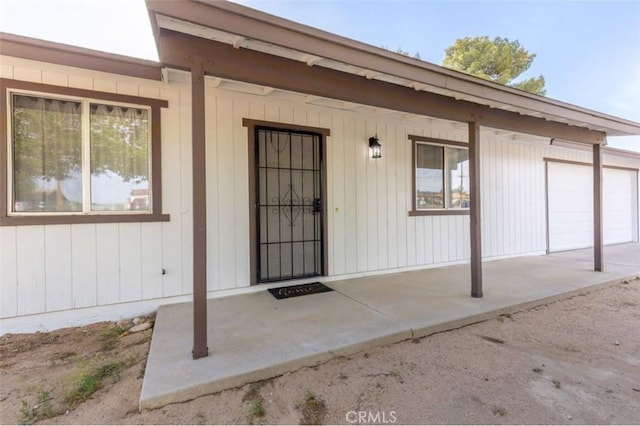 doorway to property with covered porch and a garage