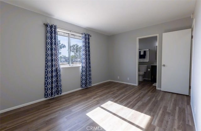 empty room featuring wood finished floors and baseboards