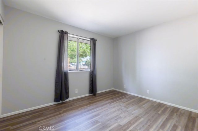 spare room featuring wood finished floors and baseboards