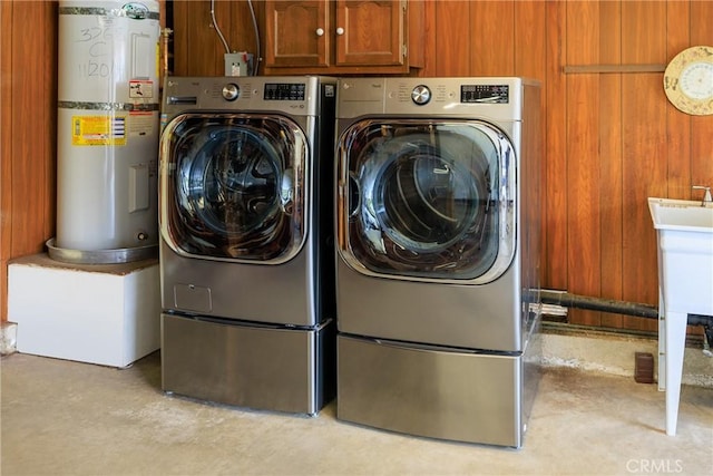 3268 San Amadeo Unit C, Laguna Woods, CA 92637 - clothes washing area with water heater, washing machine and dryer, wood walls, and cabinet space