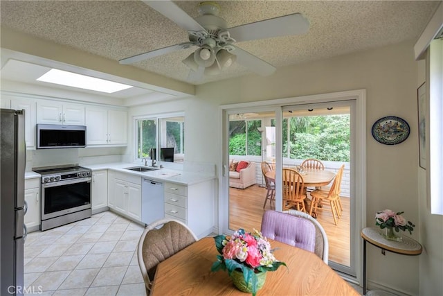 3268 San Amadeo Unit C, Laguna Woods, CA 92637 - kitchen featuring appliances with stainless steel finishes, a sink, white cabinetry, light countertops, and a textured ceiling