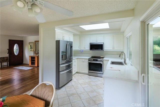 3268 San Amadeo Unit C, Laguna Woods, CA 92637 - kitchen featuring appliances with stainless steel finishes, a sink, a skylight, light countertops, and white cabinets