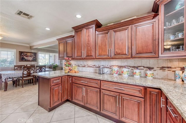kitchen featuring ornamental molding, light tile patterned floors, light stone counters, tasteful backsplash, and brown cabinets