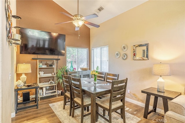 dining space featuring wood finished floors, a ceiling fan, baseboards, and lofted ceiling