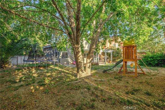 view of playground with a trampoline, fence, and a pergola